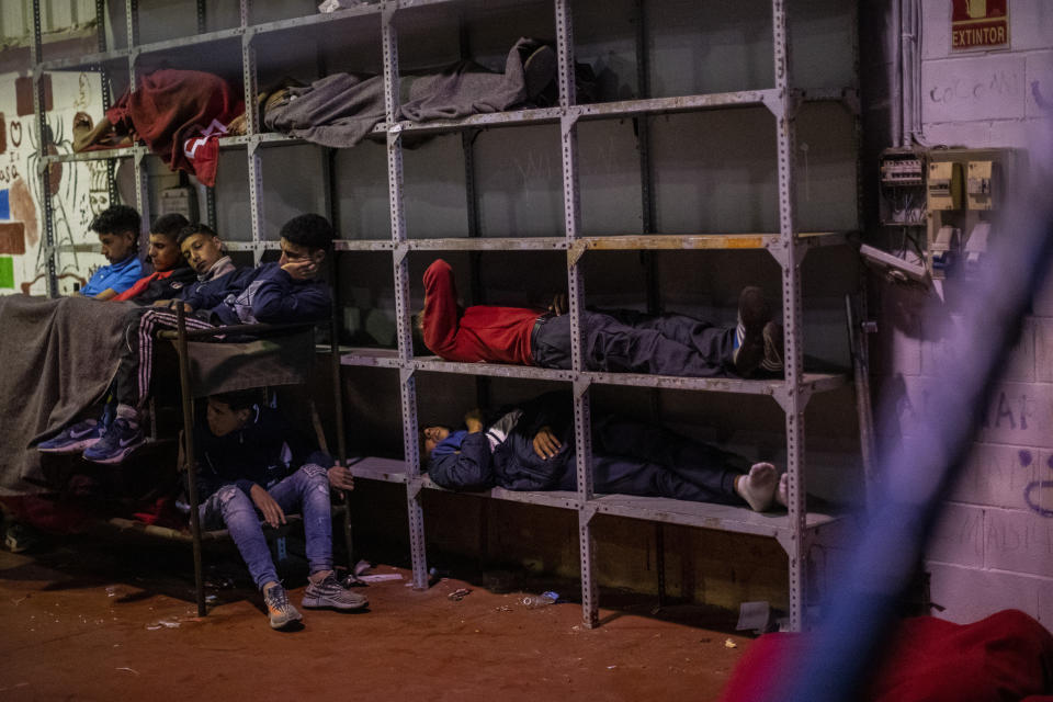 Minors sleep inside a warehouse turned into a makeshift center for migrant minors at the Spanish enclave of Ceuta, at the border of Morocco and Spain, early Wednesday, May 19, 2021. About 8,000 people have streamed into the Spanish city of Ceuta from Morocco in the past two days in an unprecedented influx of migrants, most of them swimming across the border to reach the Spanish enclave in North Africa. (AP Photo/Bernat Armangue)