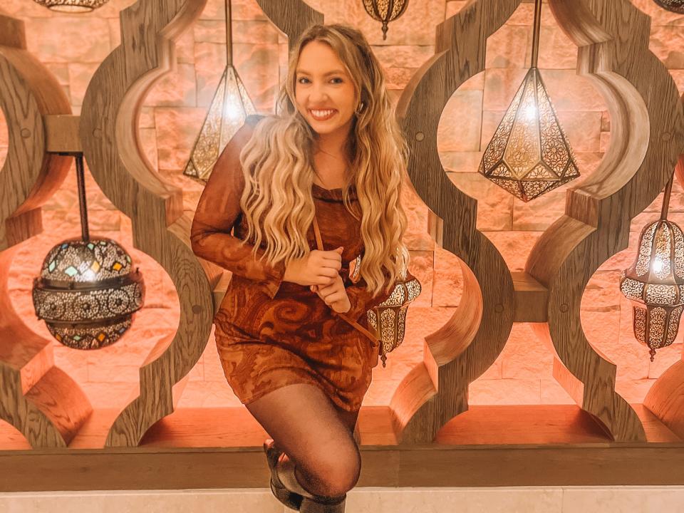 kayleigh posing in front of a wall of decorative lamps in a lobby at disney's coronado springs resort