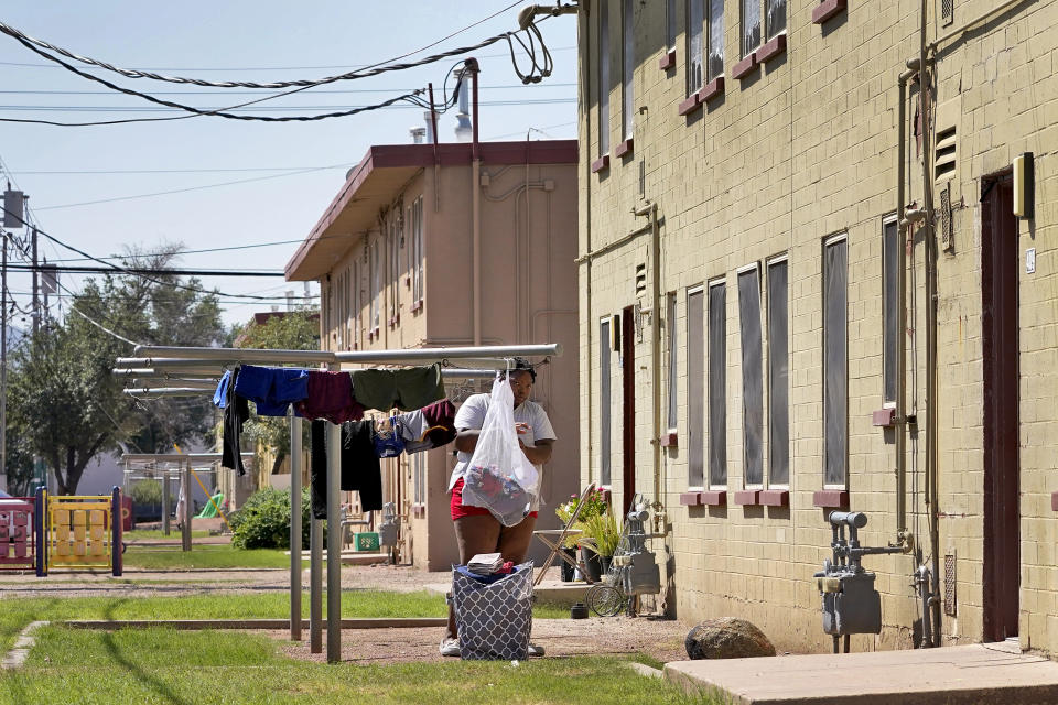 FILE - A woman hangs laundry outside a pubic housing building, Monday, Sept. 13, 2021, in Phoenix. Extreme heat is not only uncomfortable, it's expensive. That's the conclusion of a study presented Monday, Dec. 6, 2021, by The Nature Conservancy, which commissioned a look at the costs of rising temperatures in Phoenix, the hottest large metropolitan area in the U.S. (AP Photo/Matt York,File)