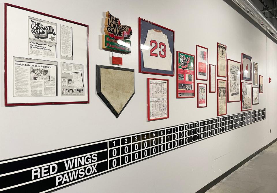 A collection of photographs and items commemorating the longest game in professional baseball between the Pawtucket Red Sox and the Rochester Red Wings hangs on a wall inside Polar Park.