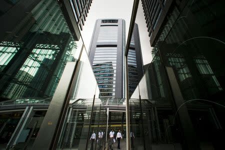 People walk in the shadows of office skyscrapers in a business district in Tokyo August 20, 2015. REUTERS/Thomas Peter