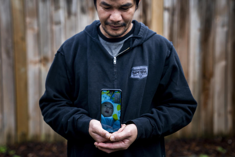 Seafarer Norberto Cabrela stands for a portrait while on a video call with his infant son, who he had not been able to meet in person, at a temporary rental house in Lacey, Wash., on Tuesday, Jan. 30, 2024. While waiting for backpay, stuck in the U.S., Cabrela missed the birth of his son, then scrambled to find the money to pay the hospital bills. (AP Photo/Lindsey Wasson)
