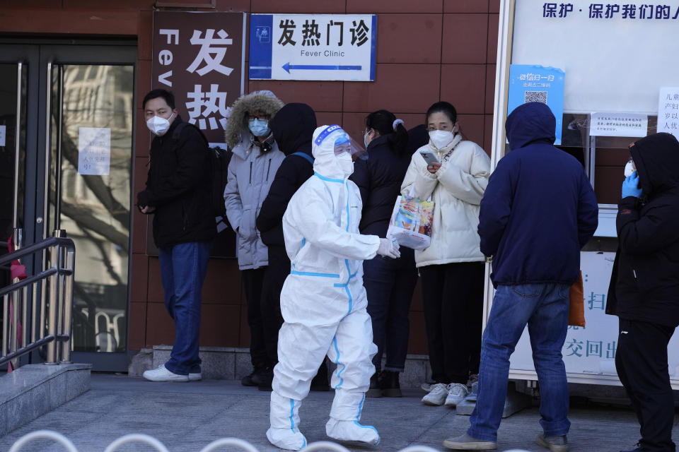 A worker in protective overalls controls the line outside the fever clinic at a hospital in Beijing, Saturday, Dec. 10, 2022. A rash of COVID-19 cases in schools and businesses were reported Friday in areas across China after the ruling Communist Party loosened anti-virus rules as it tries to reverse a deepening economic slump. (AP Photo/Ng Han Guan)