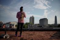 Foto del saxofonista Michel Herrera actuando ante una cámara de TV (fuera de la imagen) en la terraza de su edificio en La Habana, en medio de la pandemia del coronavirus