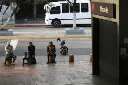 Locals sit outside a closed metro station during a blackout in Caracas, Venezuela March 27, 2019. REUTERS/Ivan Alvarado