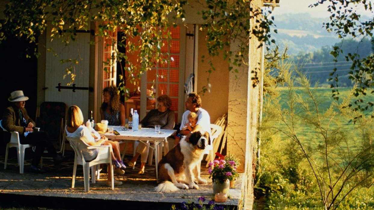 A Saint Bernard sits next to a family at an outdoor dining table