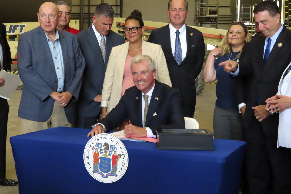 New Jersey Gov. Phil Murphy signs a bill in Paulsboro, N.J., Thursday, July 6, 2023, granting a tax break to offshore wind energy developer Orsted. (AP Photo/Wayne Parry)