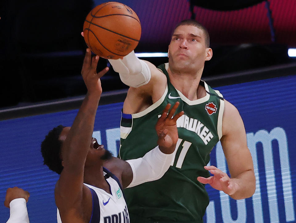 Dallas Mavericks' Dorian Finney-Smith, left, and Milwaukee Bucks' Brook Lopez (11) tangle while going after a rebound during an NBA basketball game Saturday, Aug. 8, 2020, in Lake Buena Vista, Fla. (Kevin C. Cox/Pool Photo via AP)