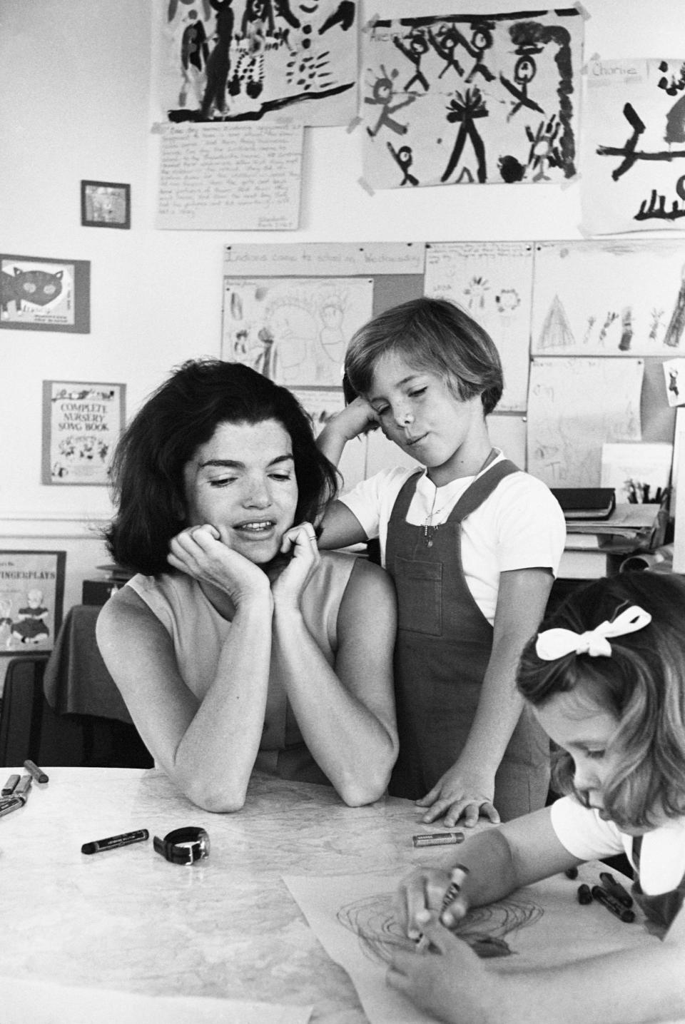 Jackie Kennedy and Caroline Kennedy watch a student draw at the White House kindergarten.