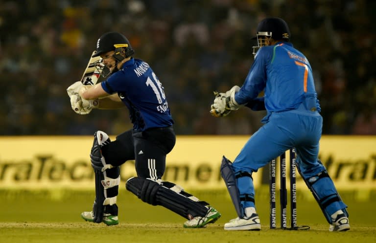 England's captain Eoin Morgan (L) hits a shot as India's wicket keeper Mahindra Singh Dhoni looks on during the second One Day International cricket match between India and England at the Barabati Stadium in Cuttack on January 19, 2017