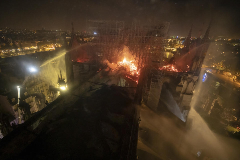 This aerial photo provided Tuesday April 16, 2019 by the Paris Fire Brigade shows Notre Dame cathedral burning, Monday April 15, 2019. Experts assessed the blackened shell of Paris' iconic Notre Dame Tuesday morning to establish next steps to save what remains after a devastating fire destroyed much of the cathedral that had survived almost 900 years of history. (Benoit Moser/BSPP via AP)