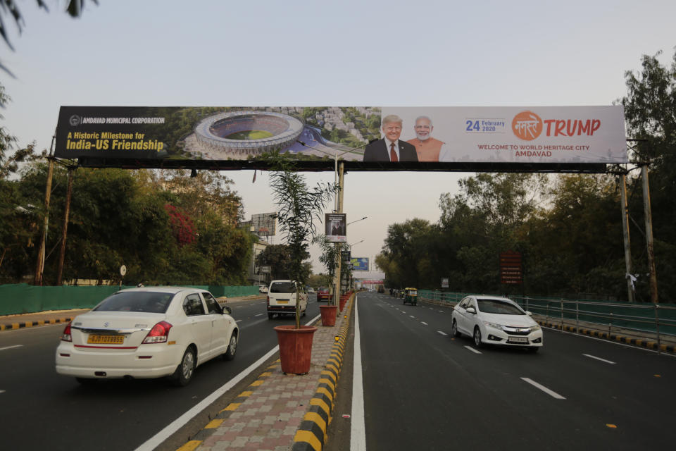FILE - In this Feb. 19, 2020, file photo, vehicles move past a hoarding welcoming U.S. President Donald Trump ahead of his visit to Ahmedabad, India. A festive mood has enveloped Ahmedabad in India’s northwestern state of Gujarat ahead of Prime Minister Narendra Modi's meeting Monday with U.S. President Donald Trump, whom he's promised millions of adoring fans. The rally in Modi's home state may help replace his association with deadly anti-Muslim riots in 2002 that landed him with a U.S. travel ban. It may also distract Indians, at least temporarily, from a slumping economy and ongoing protests over a citizenship law that excludes Muslims, but also risks reopening old wounds. (AP Photo/Ajit Solanki, File)