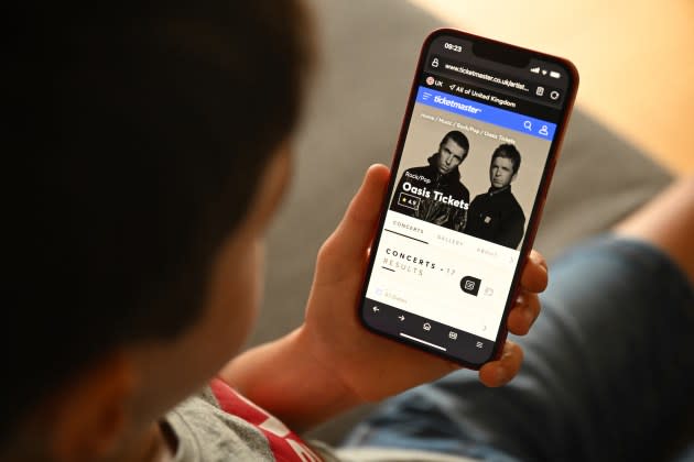 A fan uses a smartphone to access an on-line ticket sales website to purchase tickets for Oasis' "Live '25" tour. - Credit: Oli Scarff/AFP via Getty Images