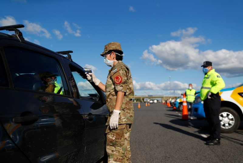A member of the Argentine border police takes the temperature of a driver for precaution due to coronavirus disease (COVID-19), in Buenos Aires