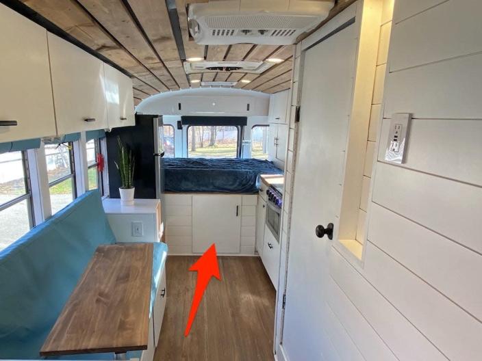 An arrow points to the door leading to a storage area of the bus.