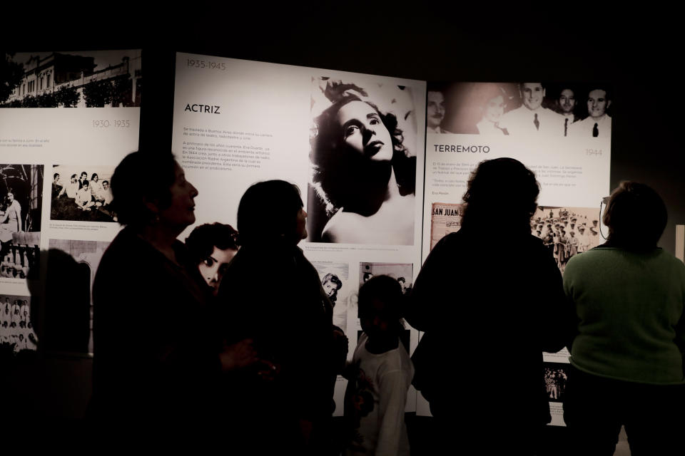 Visitors look at pictures of Eva Perón on display inside the home-turned-museum "Casa Museo Eva Perón" in Los Toldos, Argentina, Monday, May 6, 2019. One day ahead of the 100th anniversary of Evita's birth, the home where Argentina's mythical first lady was born and raised was opened to the public with an exhibition recounting the childhood of the woman who, together with her husband Juan Domingo Perón, will forever mark Argentine history. (AP Photo/Natacha Pisarenko)