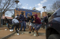 Protesters run for cover as they clash with police at Eldorado Park police station in Johannesburg, South Africa, Thursday, Aug. 27, 2020. Residents from the township, south of Johannesburg are demanding justice for a teenager shot and killed, allegedly at the hands of police Wednesday. (AP Photo/Themba Hadebe)