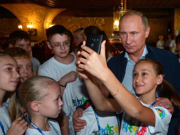 A girl takes a self portrait with Russian President Vladimir Putin as he vists a sports center for children in the Black Sea resort of Sochi, Russia, Saturday, Oct. 11, 2014.