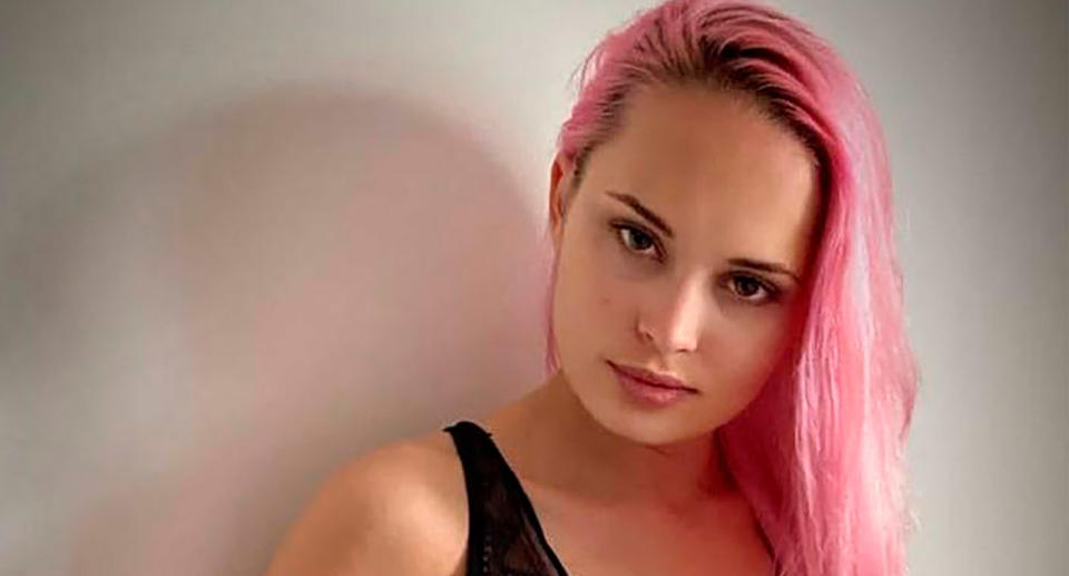 Valentina ‘Valya’ Grigoryeva poses in front of a wall with pink-dyed hair. 