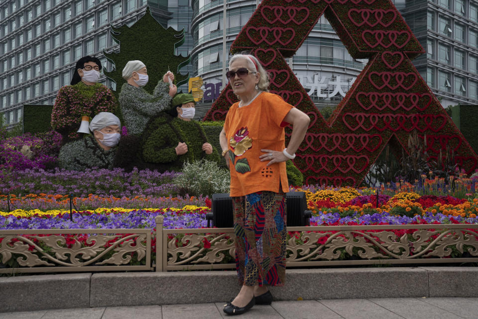 A woman poses for photos near floral decorations, honoring China's frontline workers who fought the COVID-19 outbreak, setup for the National Day holidays in Beijing on Monday, Sept. 28, 2020. Negative perceptions of China have increased sharply in many of the world's advanced economies, especially in Australia and the U.K., a new survey from the Pew Research Center showed Tuesday, Oct. 6, 2020. (AP Photo/Ng Han Guan)