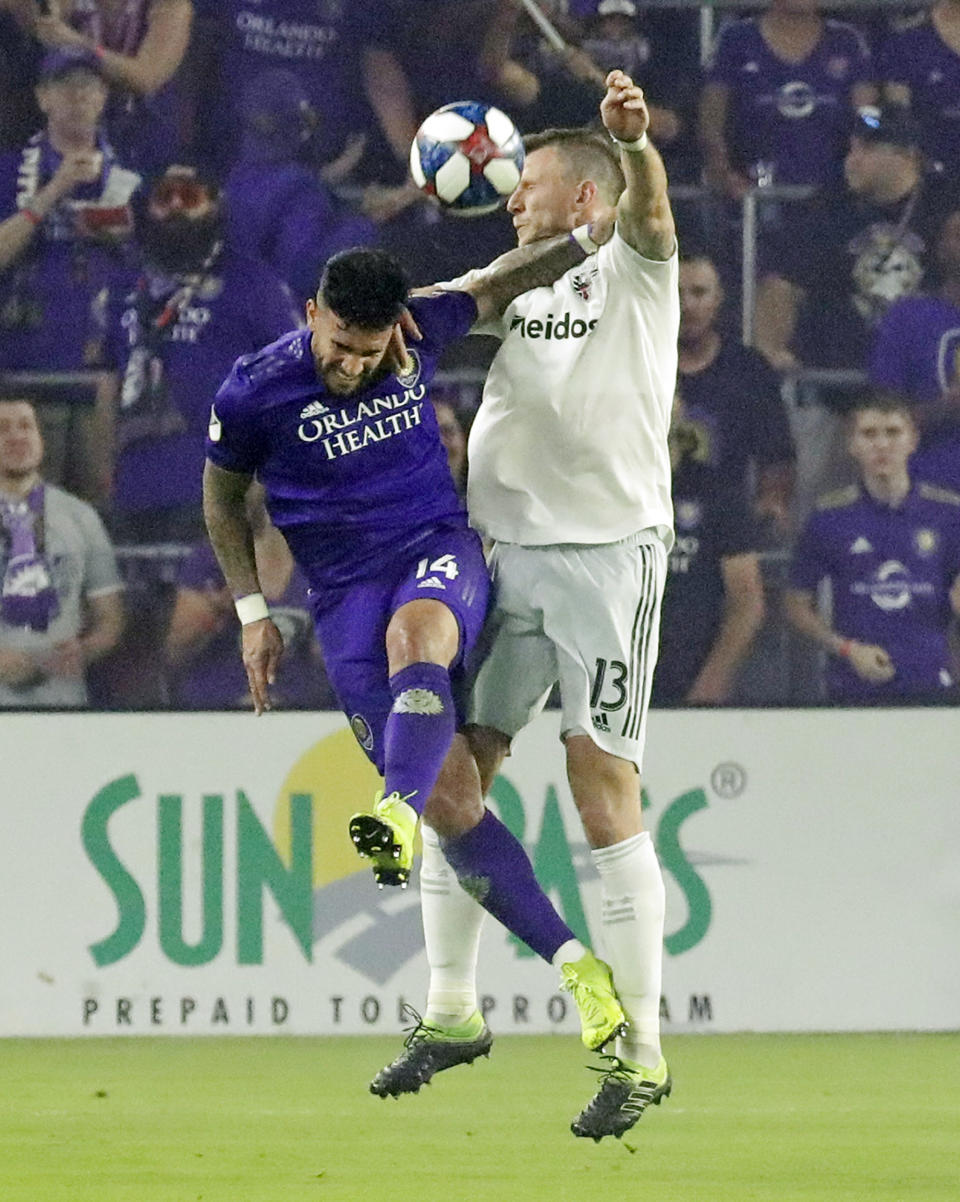 Orlando City's Dom Dwyer, left, and D.C. United's Frederic Brillant, right, battle for a header during the second half of an MLS soccer match, Sunday, March 31, 2019, in Orlando, Fla. (AP Photo/John Raoux)