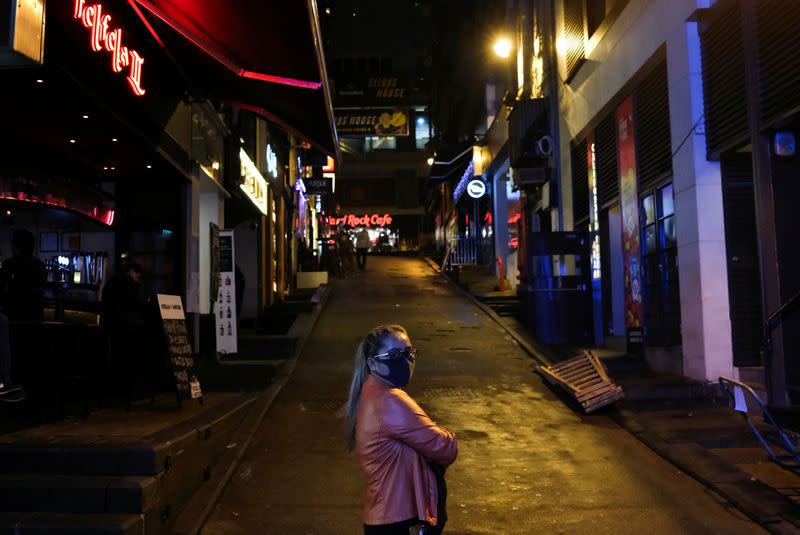 A woman stands outside an almost empty pubs area, following the novel coronavirus disease (COVID-19) outbreak, at Lan Kwai Fong, a popular nightlife destination in Central, Hong Kong