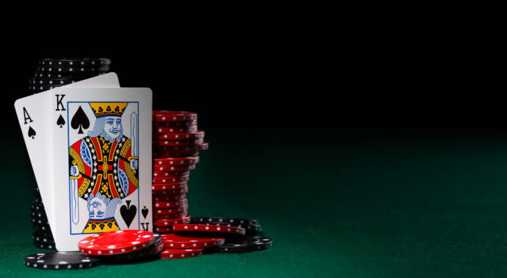 two playing cards, an ace of spades and a king of spades, leaned against a stack of black and red poker chips. represents gambling stocks.
