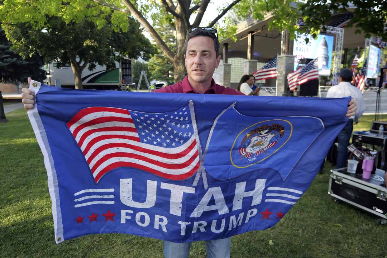 Trent Staggs, at a rally, carries a flag reading: Utah for Trump.