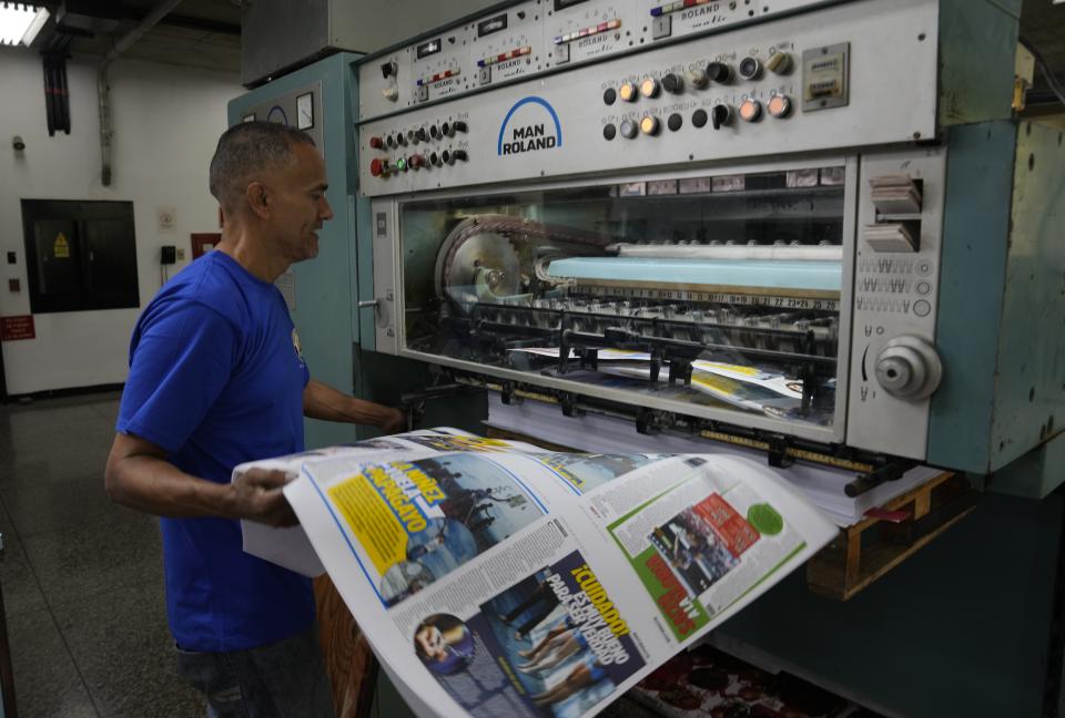 A worker handles a sample of the newspaper "Enterate," at a private printing shop in Caracas, Venezuela, Monday, July 26, 2021. Journalists are giving free copies of "Enterate" to bus passengers and people at bus stops, and encouraging them to share the papers with others. (AP Photo/Ariana Cubillos)