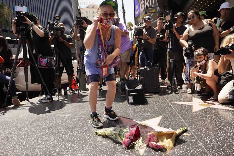 A fan honors actor Olivia Newton-John with flowers on Newton-John's Hollywood Walk of Fame star in Los Angeles, Monday, Aug. 8, 2022. Newton-John, the Grammy-winning superstar who reigned on pop, country, adult contemporary and dance charts with such hits as "Physical" and "You're the One That I Want" has died. She was 73. (AP Photo/Damian Dovarganes)