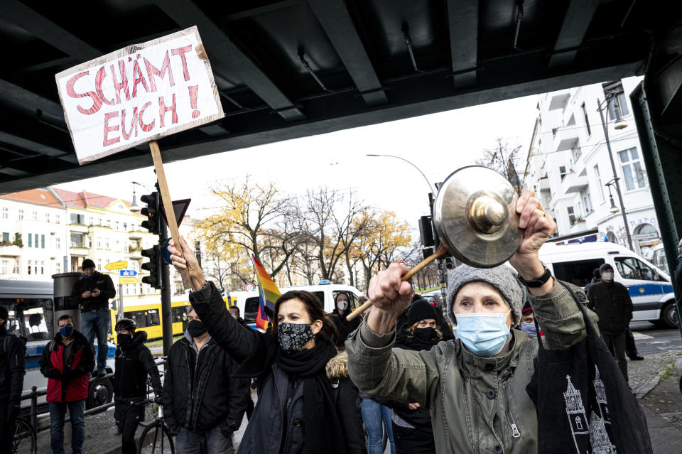 Counter demonstrators shows a poster reading: 'shame on you' as the protest against a so called 'silent march' against the corona policy of the federal government, at the district Prenzlauer Berg in Berlin Germany, Sunday, Nov. 22, 2020. (Fabian Sommer/dpa via AP)