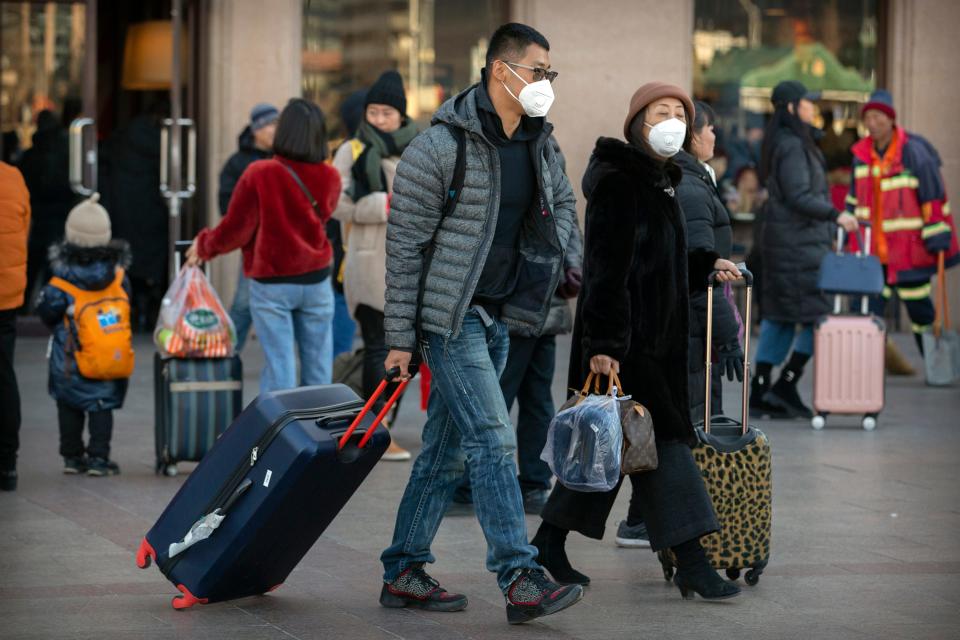 Travelers wear face masks as they walk outside of the Beijing Railway Station in Beijing, Monday, Jan. 20, 2020. China reported Monday a sharp rise in the number of people infected with a new coronavirus, including the first cases in the capital.