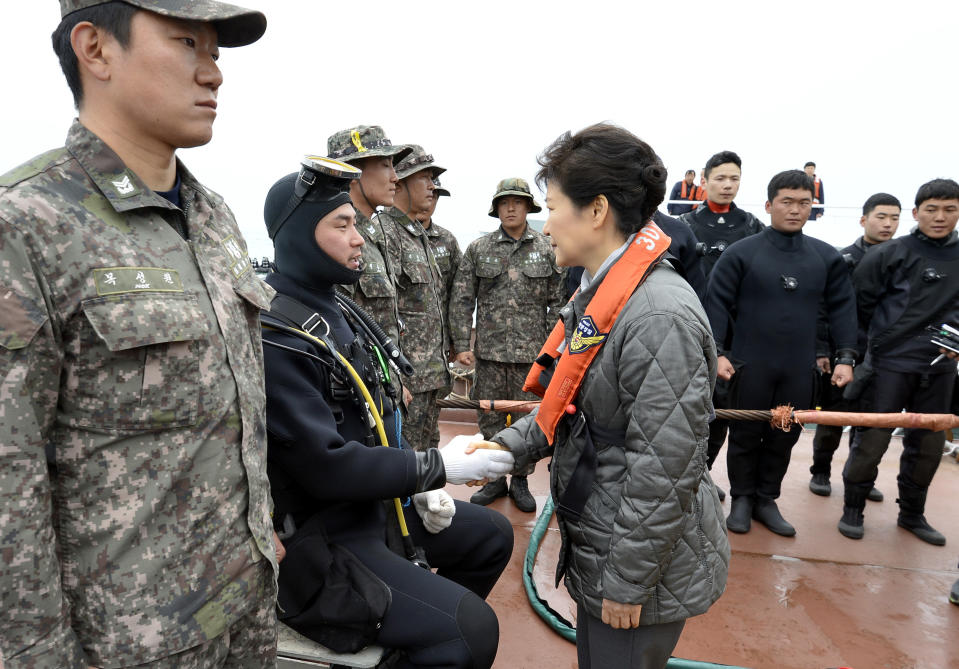 South Korean President Park Geun-hye, right, shakes hands with a diver at the site where the Sewol ferry sank in waters off the southern coast near Jindo, South Korea, Sunday, May 4, 2014. Park told families of those missing in the sunken ferry that her heart breaks knowing what they are going through, as divers recovered two more bodies on Sunday. (AP Photo/Yonhap) KOREA OUT