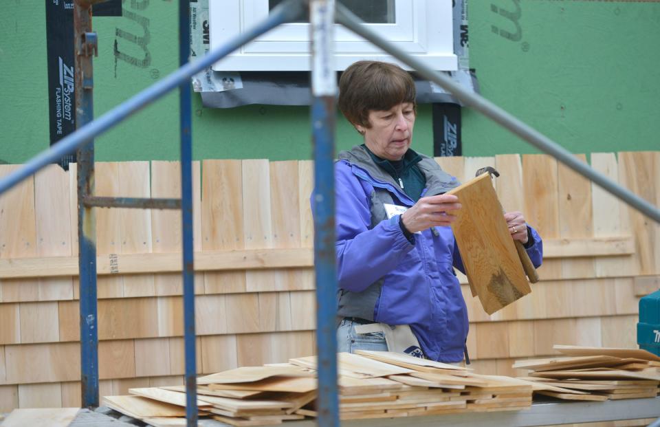 Sharon Dixon of William Raveis Real Estate selects a cedar shingle to hammer into this Habitat for Humanity of Cape Cod home in Brewster. A group of real estate agents from William Raveis Real Estate were volunteering their time Thursday for the house build. Two new Habitat for Humanity of Cape Cod homes are being built on Phoebe Way. The homes are constructed on property that Elizabeth Finch subdivided. Finch's home remains on the nearly 58,000-square-foot lot. To see more photos, go to www.capecodtimes.com.