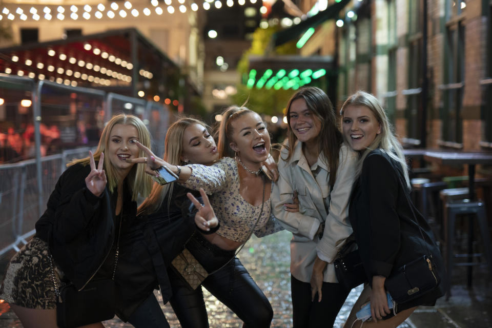 Young people pose for a photo, outside a bar in Liverpool after Prime Minister Boris Johnson laid out a new three-tier alert system for England, in Liverpool, England, Monday Oct. 12, 2020. The British government has carved England into three tiers of risk in a bid to slow the spread of a resurgent coronavirus. The northern city of Liverpool is in the highest category and will close pubs, gyms and betting shops. (AP Photo/Jon Super)