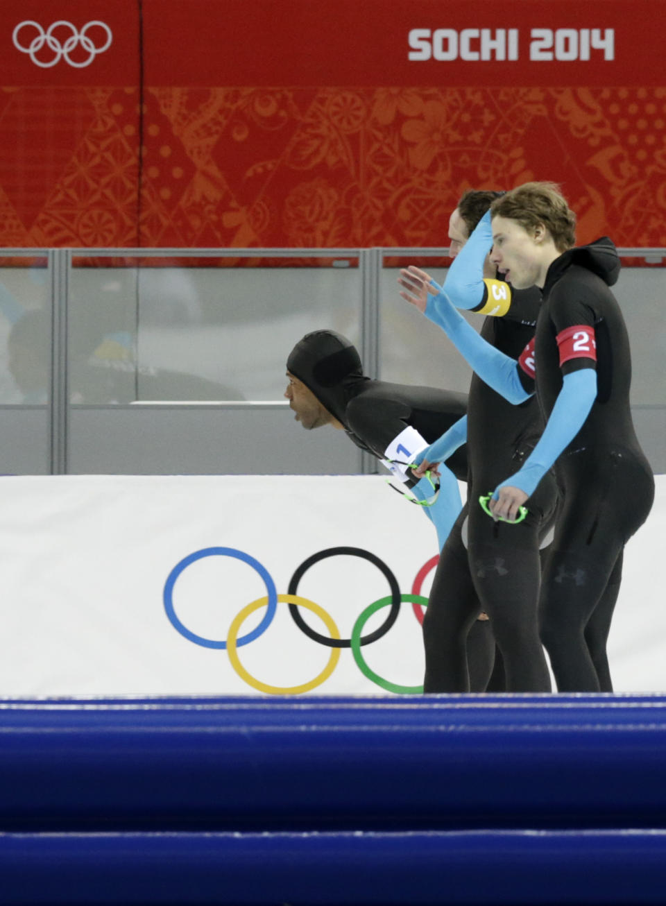 The U.S. speedskating team, Shani Davis, bending, Jonathan Kuck, background, and Brian Hansen catch their breath after competing in the men's speedskating team pursuit quarterfinals at the Adler Arena Skating Center during the 2014 Winter Olympics in Sochi, Russia, Friday, Feb. 21, 2014. (AP Photo/Matt Dunham)