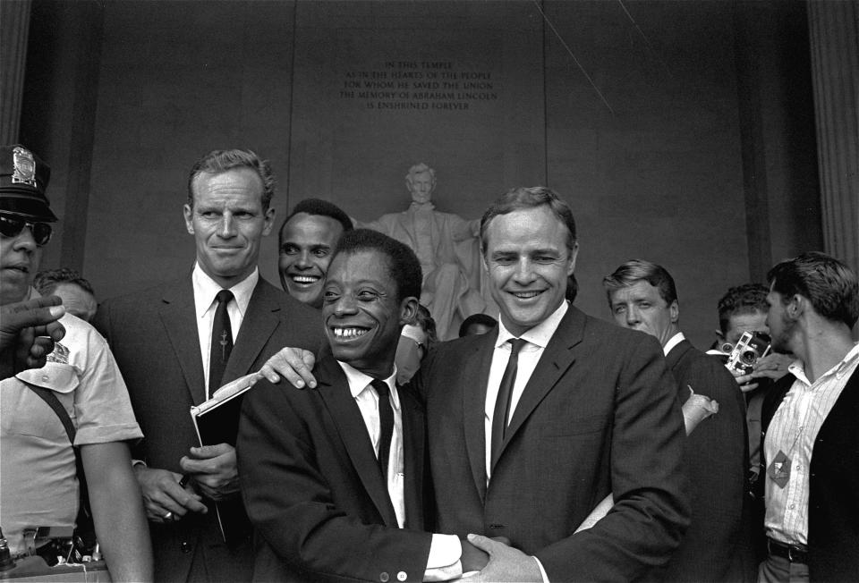 Marlon Brando, right, poses with his arm around author and civil rights leader James Baldwin at the Lincoln Memorial during the March on Washington in 1963. Posing with them are actors Charlton Heston, left, and Harry Belafonte.