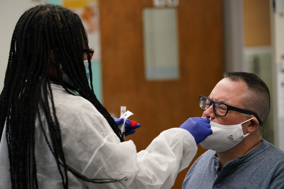 Instructor Frank Esposito submits to a COVID-19 nasal swab test at West Brooklyn Community High School, Thursday, Oct. 29, 2020, in New York. The high school is a "transfer school," catering to a students who haven't done well elsewhere, giving them a chance to graduate and succeed. The school reopened Monday after it was forced to shut down for three weeks due to a coronavirus outbreak in the immediate neighborhood. (AP Photo/Kathy Willens)