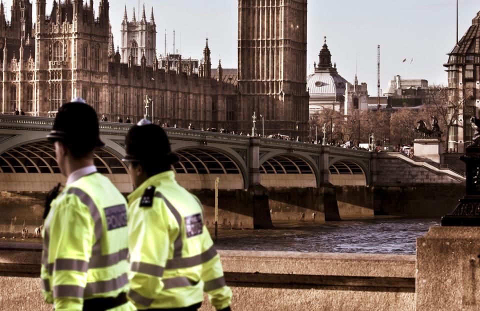 Two London police walking in front of a bridge.