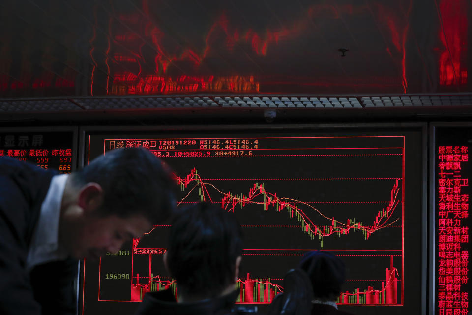 Chinese investors monitor stock prices near an electronic screen displaying composite index at a brokerage house in Beijing, Friday, Dec. 20, 2019. Stocks were mixed in early trading in Asia on Friday after Wall Street posted more record highs, extending the market's gains for the week. (AP Photo/Andy Wong)