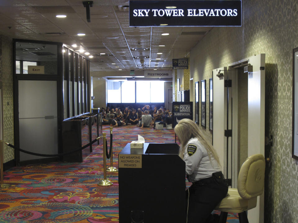 A security guard sits at a check point next to the elevators while University of Nevada resident assistants sit in the background on Aug. 19, 2019 during a training session at the Circus Circus casino hotel tower that's been converted into a residence hall. Renamed Wolf Pack Tower, it will house about 1,300 students this school year after a gas explosion in July shut down two major dorms on the main campus a half-mile away. (AP Photo/Scott Sonner)