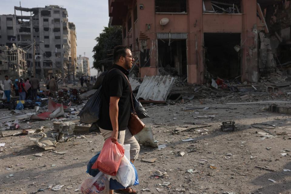 A man carrying bags filled with his belongings leaves a bombed area in Gaza City (AFP/Getty)