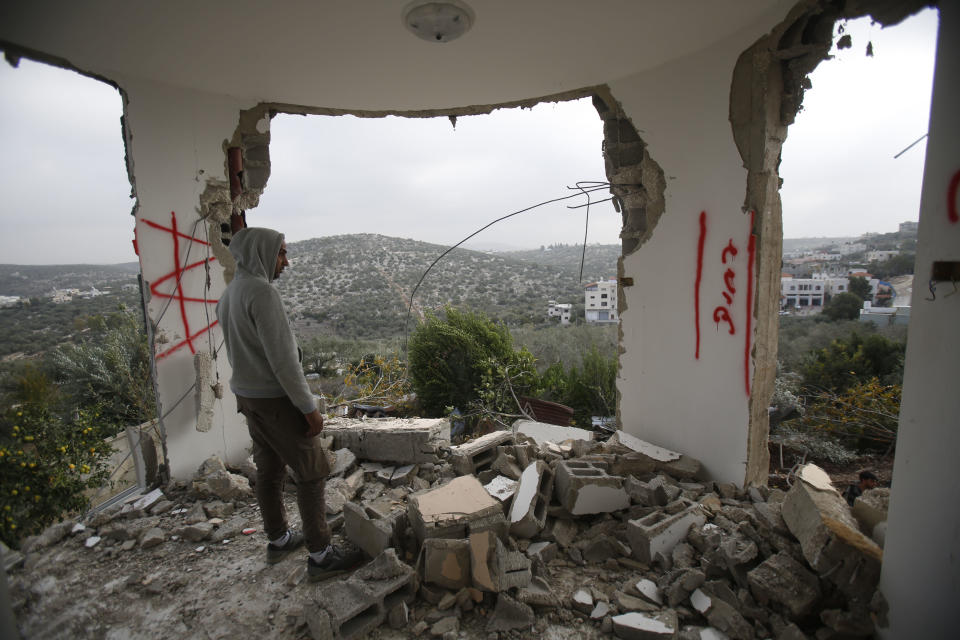 A Palestinian man examines a house after it was partially demolished by the Israeli army in the village of Shweikeh, near the West Bank city of Tulkarem, Monday, Dec. 17, 2018. The Israeli military has partially demolished the home of Ashraf Naalweh, a Palestinian accused of killing two Israelis in a West Bank attack two months ago. (AP Photo/Majdi Mohammed)