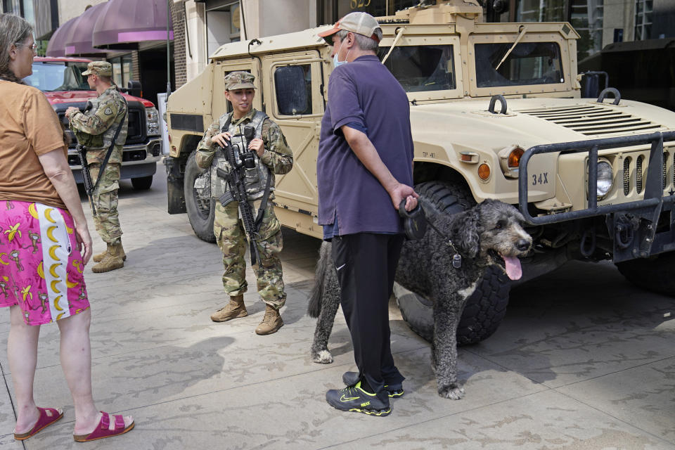 A pedestrian with a Bernard Poodle dog visits with Minnesota National Guard soldiers along the famous Nicollet Mall Thursday, Aug. 27, 2020, in downtown Minneapolis. An emergency curfew expired and downtown Minneapolis was calm Thursday morning after a night of unrest that broke out following what authorities said was misinformation about the suicide of a Black homicide suspect. (AP Photo/Jim Mone)