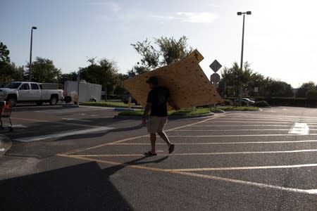 A man carries a sheet of plywood at a Home Depot store ahead of the arrival of Hurricane Dorian in Titusville