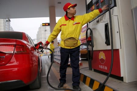 FILE PHOTO: A gas station attendant pumps fuel into a customer's car at a PetroChina petrol station in Beijing