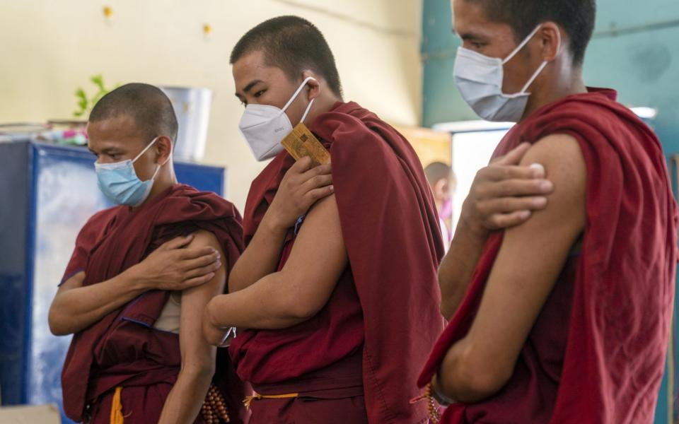 Buddhist monks hold their arms after receiving a Covid-19 vaccine in Dharamshala, Himachal Pradesh, India, on 1 July 2021  - Sumit Dayal/Bloomberg