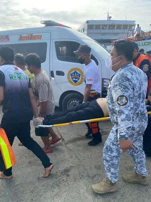 Philippine Coast Guard personnel carry a rescued passenger after a passenger vessel carrying more than 100 people caught fire near Real