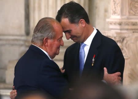 Spain's King Juan Carlos and his son Crown Prince Felipe (R) embrace during the signature ceremony of his act of abdication at the Royal Palace in Madrid, in this file picture taken June 18, 2014. REUTERS/Juan Medina/Files