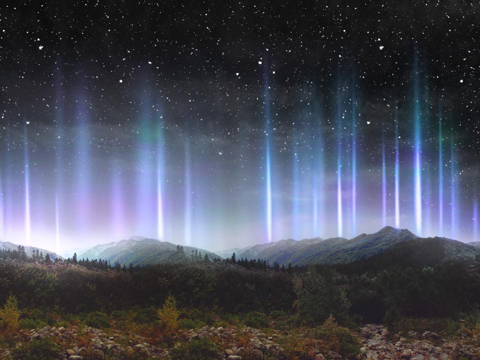 colorful light pillars at night over the mountains